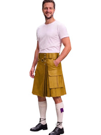 A man modeling a mustard yellow faux-leather kilt with a matching belt and metal hardware, paired with a white t-shirt, white knee-high socks, and black shoes, on a solid white background.