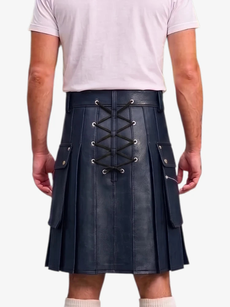 A man wearing a dark navy blue faux-leather kilt with a lace-up back closure, side pockets, and pleated front panels, paired with a light pink t-shirt and white socks.