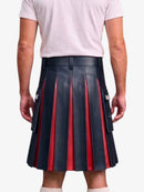 A person shown from the back wearing a pleated leather kilt with alternating dark navy and red vertical pleats, paired with a light pink t-shirt and white socks, against a plain light gray background.