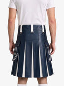A man wearing a navy blue faux-leather pleated kilt with white vertical stripe details and white suspenders, paired with a white t-shirt, shown from the back against a light gray background.