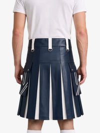 A man wearing a navy blue faux-leather pleated kilt with white vertical stripe details and white suspenders, paired with a white t-shirt, shown from the back against a light gray background.