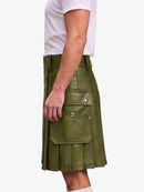 A side view of a person wearing an olive green faux-leather kilt with silver snap button details and pleated folds, paired with a white t-shirt against a light gray background.