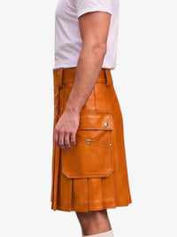 A side view of a person wearing a bright orange-brown leather kilt with flap pockets and silver snap buttons, paired with a white t-shirt against a light gray background.