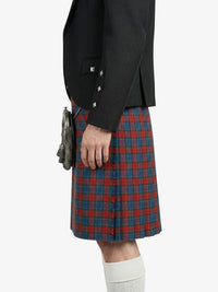 Person wearing a black blazer and red plaid kilt on a white background