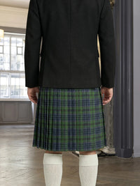 Person wearing a black jacket and green plaid kilt indoors.