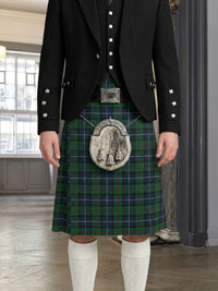Person wearing a traditional Scottish kilt with a plaid pattern in a room with large windows.