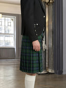 Person wearing a black jacket and green plaid kilt indoors.