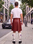A man viewed from behind wearing a white t-shirt and a reddish-brown pleated leather kilt, standing on a city sidewalk with a Mercedes-Benz car and storefronts in the background.
