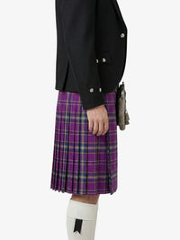 Person wearing a black jacket and purple plaid kilt on a white background