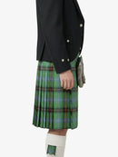 Person wearing a black jacket and green plaid kilt on a white background
