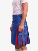 A man wearing a blue faux-leather kilt with red pleated inserts, paired with a white t-shirt and white socks, shown from the waist down against a light gray background.