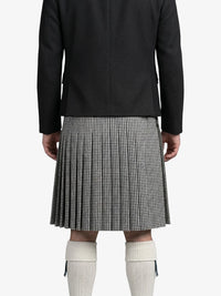 Person wearing a black coat and houndstooth pattern kilt on a white background