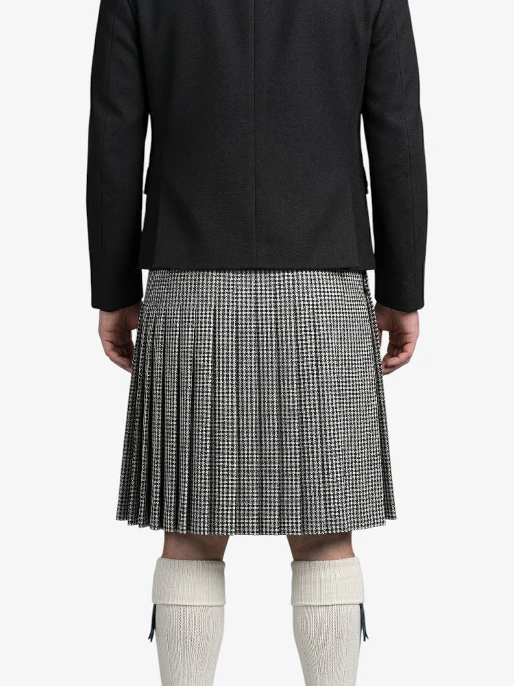 Person wearing a black coat and houndstooth pattern kilt on a white background