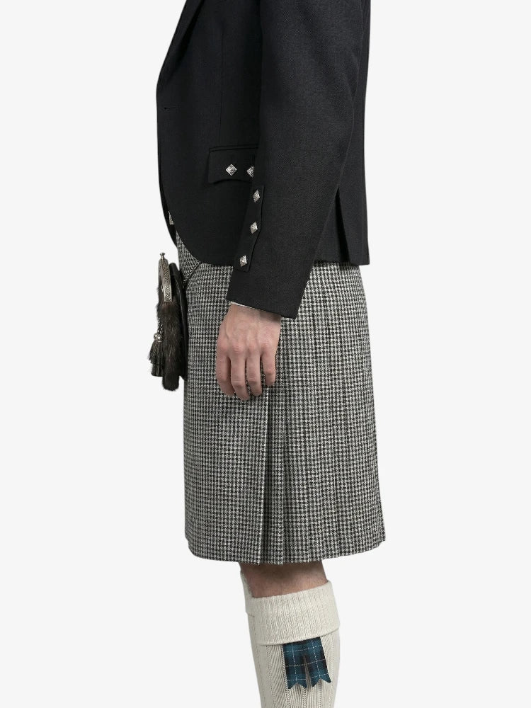 Person wearing a black jacket and gray checkered kilt on a white background
