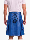 A person shown from the back wearing a bright blue pleated kilt with black lace-up detailing and side pockets, paired with a light pink T-shirt and white socks, against a plain white background.