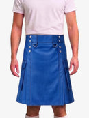 A man wearing a bright blue faux-leather kilt with silver-tone metal hardware, belt loops, and side pockets, paired with a light pink t-shirt and beige socks.