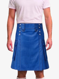 A man wearing a bright blue faux-leather kilt with silver-tone metal hardware, belt loops, and side pockets, paired with a light pink t-shirt and beige socks.