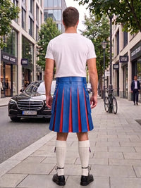 A man standing on a city sidewalk, viewed from behind, wearing a white t-shirt, a blue leather pleated kilt with red stripes, white knee-high socks, and black shoes. Buildings, trees, a parked black car, and a bicycle are visible in the background.