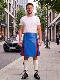 A man stands on a city sidewalk wearing a white crew-neck t-shirt and a bright blue leather kilt with red side panels, paired with cream knee-high socks and black leather shoes. The background shows a blurred street scene with a black Mercedes-Benz, storefronts, and trees.
