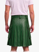 A person shown from the back wearing a dark green pleated leather kilt with side cargo pockets, paired with a light pink t-shirt and white socks, against a plain light gray background.