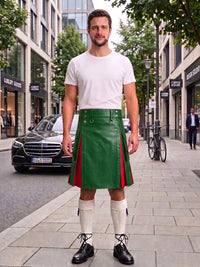 A man stands on a city sidewalk wearing a white t-shirt and a green leather kilt with red side panels, paired with white knee-high socks and black leather shoes. Buildings, trees, and a parked black car are visible in the background.
