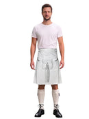 A man modeling a white faux-leather kilt costume with silver metal grommets and straps, paired with a white t-shirt, beige knee-high socks, and black shoes, against a plain white background.