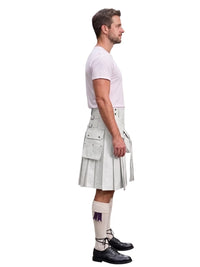 A man shown in profile wearing a white short-sleeve t-shirt and a light gray pleated kilt with utility pockets, paired with white socks and black leather shoes, against a plain white background.
