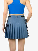 Person wearing a blue pleated skirt and blue crop top on a white background