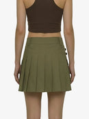 Person wearing a brown crop top and green pleated skirt on a white background